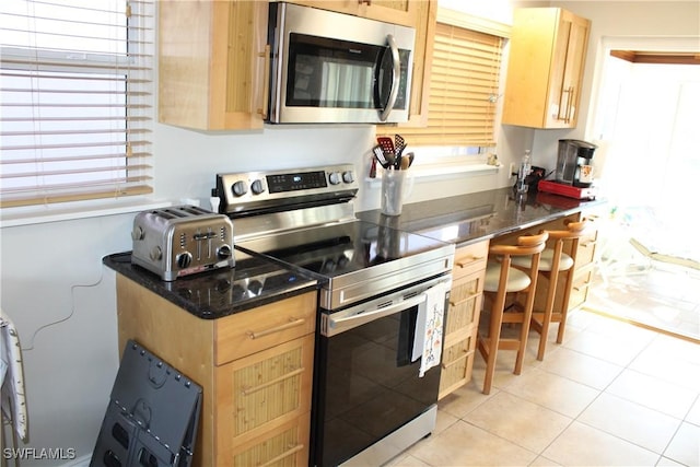 kitchen featuring light tile patterned floors, light brown cabinets, and appliances with stainless steel finishes