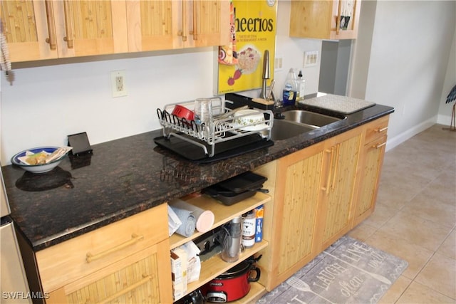 kitchen with dark stone counters, light brown cabinetry, and light tile patterned floors