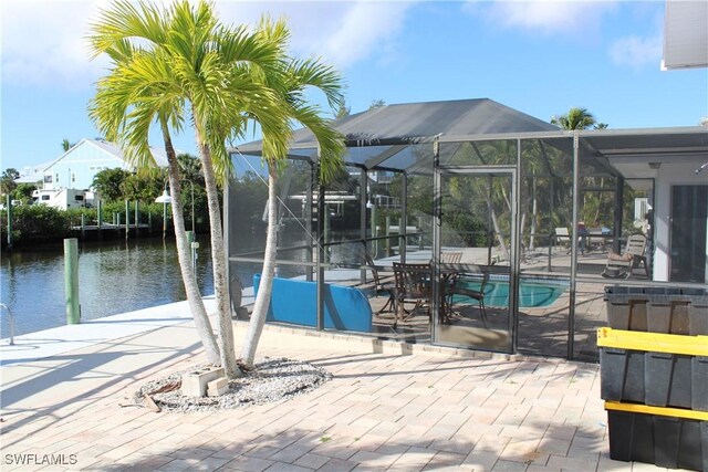 view of pool featuring a water view, a patio, and glass enclosure