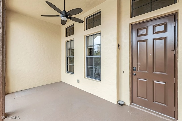 view of exterior entry featuring ceiling fan and stucco siding