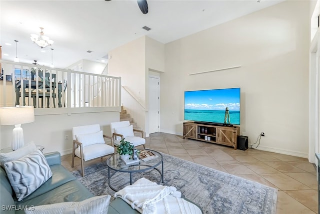 tiled living room with a towering ceiling and ceiling fan with notable chandelier