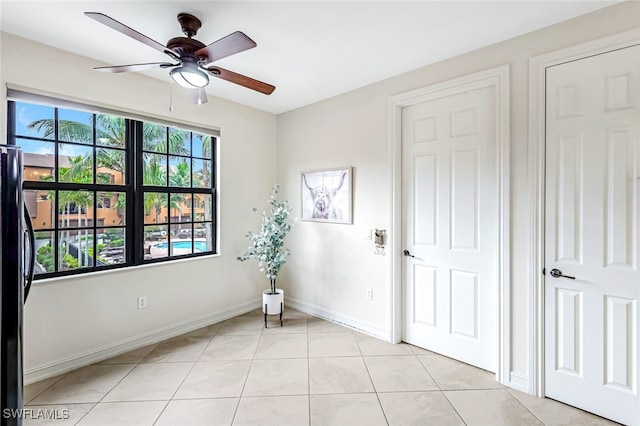 unfurnished room with light tile patterned floors, ceiling fan, and baseboards