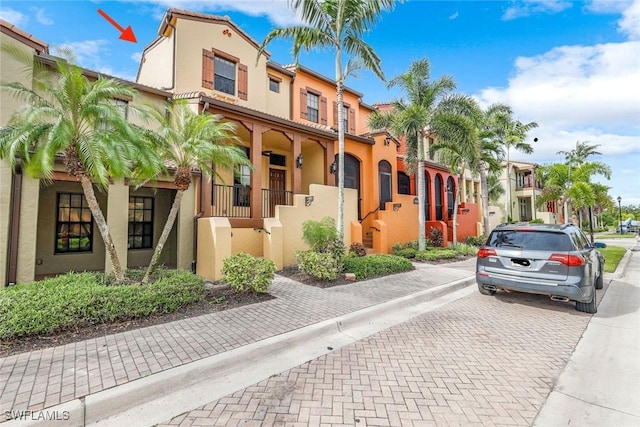 view of front of property featuring a residential view, a tile roof, and stucco siding