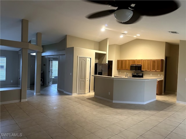 kitchen featuring lofted ceiling, light tile patterned floors, ceiling fan, appliances with stainless steel finishes, and a kitchen island with sink