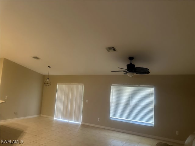 empty room featuring light tile patterned floors, ceiling fan, visible vents, and baseboards