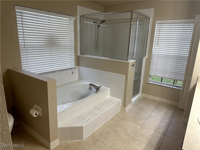 bathroom featuring toilet, a shower stall, tile patterned flooring, baseboards, and a bath