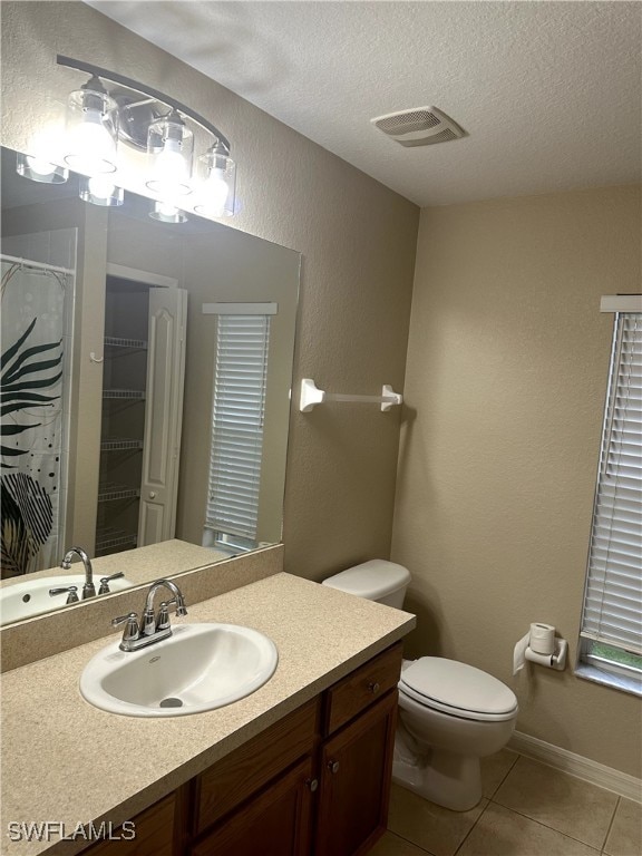 bathroom with a textured ceiling, tile patterned flooring, toilet, vanity, and visible vents