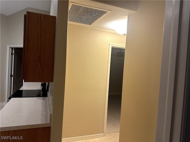 hall featuring a textured wall, light tile patterned flooring, and visible vents