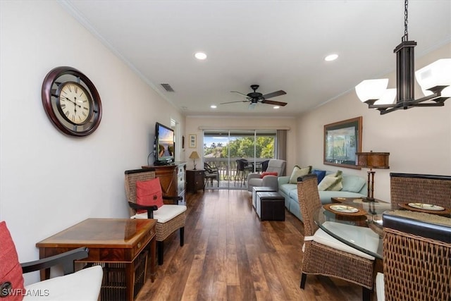 living room with crown molding, dark hardwood / wood-style floors, and ceiling fan with notable chandelier