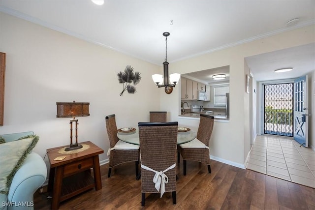 dining space with sink, crown molding, wood-type flooring, and a chandelier