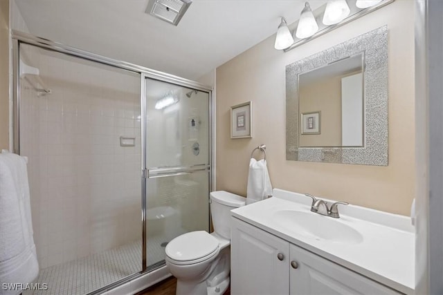 bathroom featuring vanity, a shower with door, and toilet