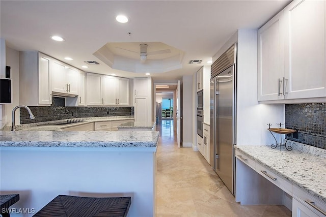 8473 Bay Colony Dr Unit 203, Naples, FL 34108 - kitchen featuring kitchen peninsula, white cabinets, and light stone countertops