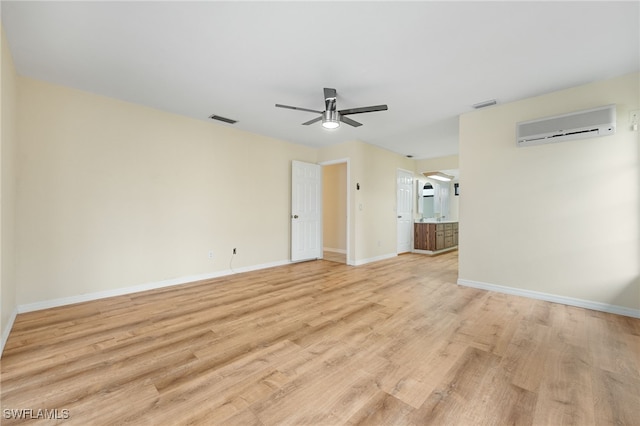 empty room featuring a wall mounted air conditioner, ceiling fan, and light wood-type flooring