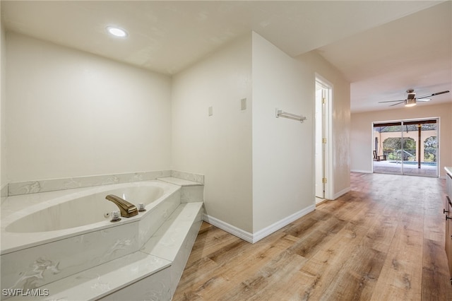 bathroom with ceiling fan, a tub to relax in, and wood-type flooring