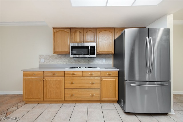 kitchen featuring appliances with stainless steel finishes, a skylight, decorative backsplash, and light tile patterned floors