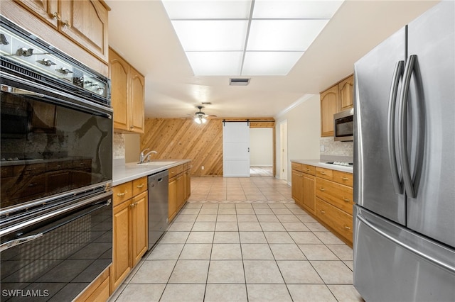 kitchen featuring light tile patterned flooring, wood walls, ceiling fan, decorative backsplash, and black appliances