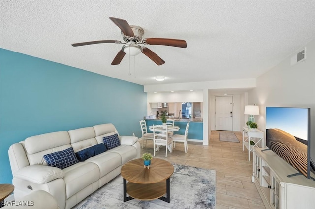 living room with ceiling fan and a textured ceiling