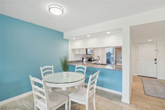 dining area featuring sink and a textured ceiling