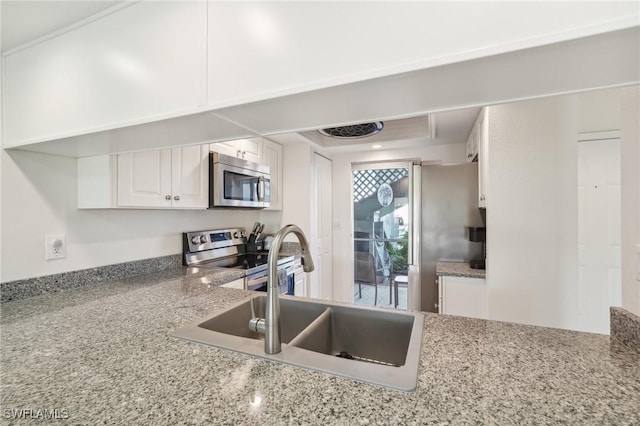 kitchen with light stone countertops, white cabinetry, appliances with stainless steel finishes, and sink