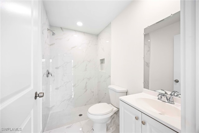 bathroom with vanity, a tile shower, and toilet