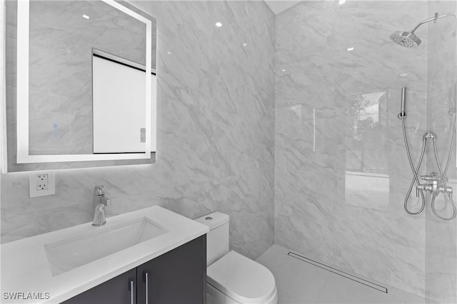 bathroom featuring vanity, tiled shower, tile walls, and toilet