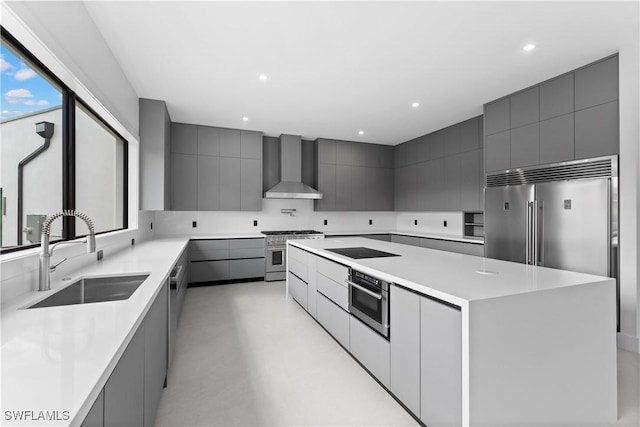 kitchen with wall chimney exhaust hood, sink, high quality appliances, gray cabinets, and a large island
