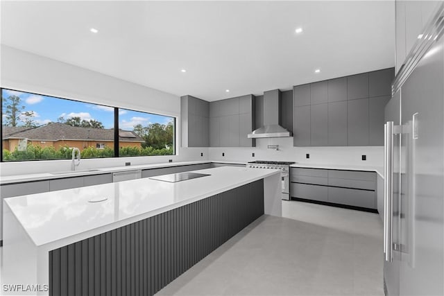 kitchen featuring sink, gray cabinets, high end appliances, a kitchen island, and wall chimney exhaust hood
