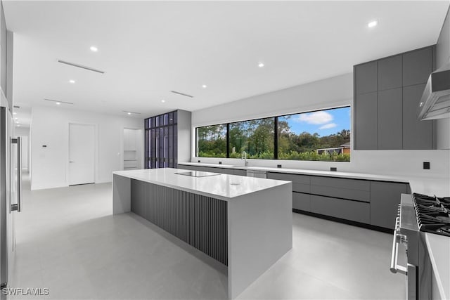 kitchen featuring gray cabinets, sink, a center island, black electric stovetop, and gas stove