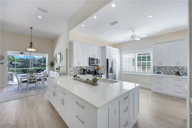 kitchen featuring white cabinetry, pendant lighting, stainless steel appliances, and a large island with sink