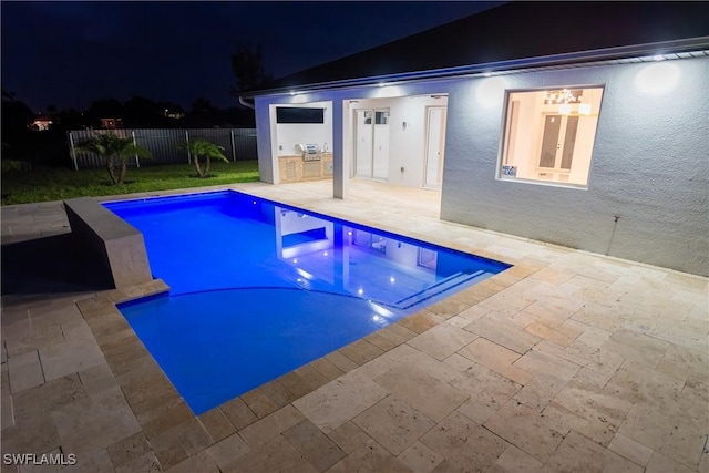 pool at twilight featuring exterior kitchen and a patio area