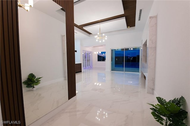 hall featuring an inviting chandelier and a raised ceiling