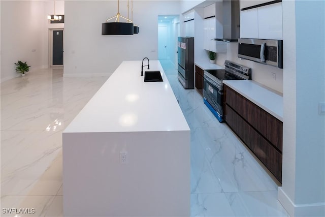 kitchen with pendant lighting, sink, appliances with stainless steel finishes, dark brown cabinetry, and a center island with sink