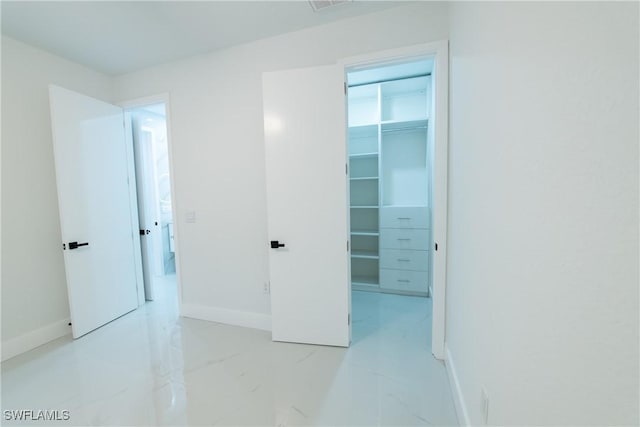 unfurnished bedroom featuring a spacious closet and a closet