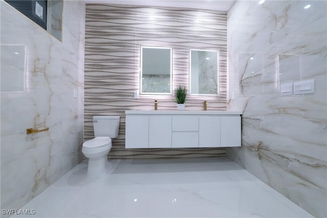 bathroom with vanity, tile walls, and toilet