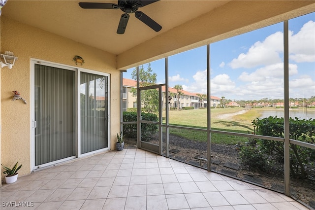 unfurnished sunroom with vaulted ceiling, ceiling fan, and a water view