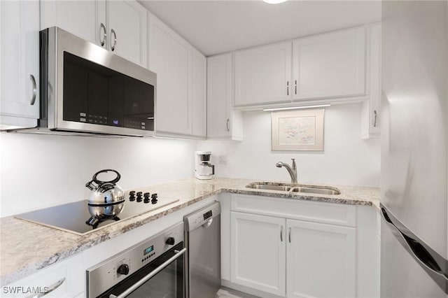 kitchen featuring appliances with stainless steel finishes, light stone countertops, sink, and white cabinets