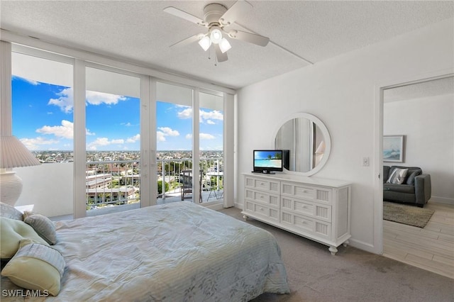 carpeted bedroom featuring expansive windows, ceiling fan, access to exterior, and a textured ceiling