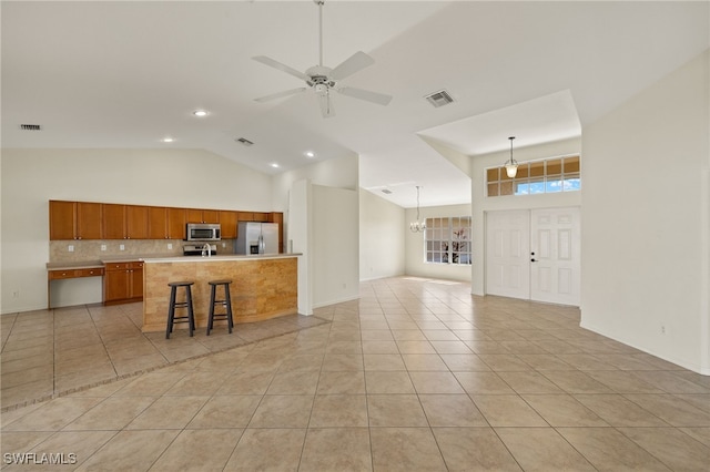 kitchen featuring an island with sink, a kitchen breakfast bar, hanging light fixtures, light tile patterned floors, and stainless steel appliances