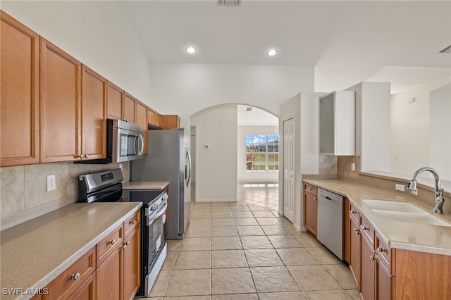 kitchen featuring sink, decorative backsplash, stainless steel appliances, and light tile patterned floors