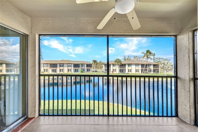 unfurnished sunroom featuring a water view, a residential view, and a ceiling fan