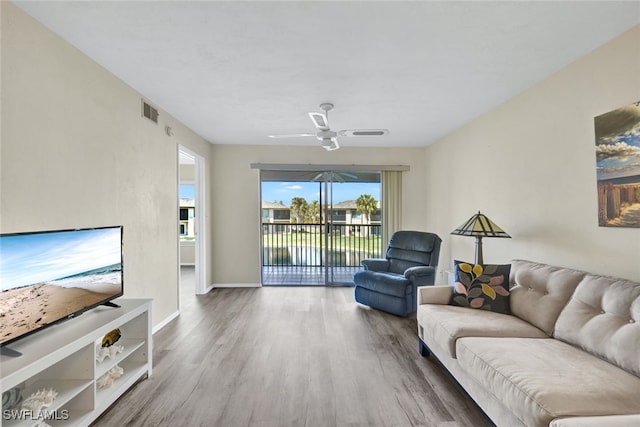 living area featuring visible vents, ceiling fan, baseboards, and wood finished floors