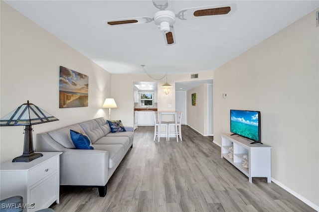 living room with light hardwood / wood-style flooring and ceiling fan