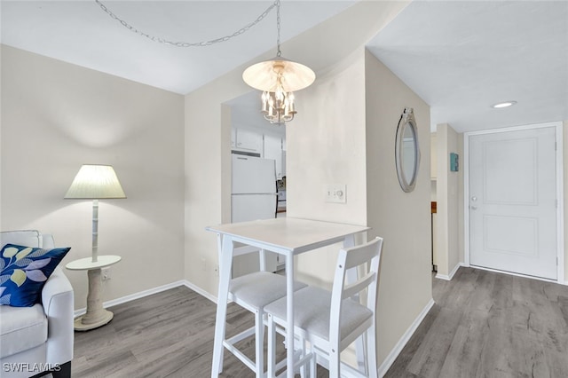 dining space with a notable chandelier, baseboards, and wood finished floors