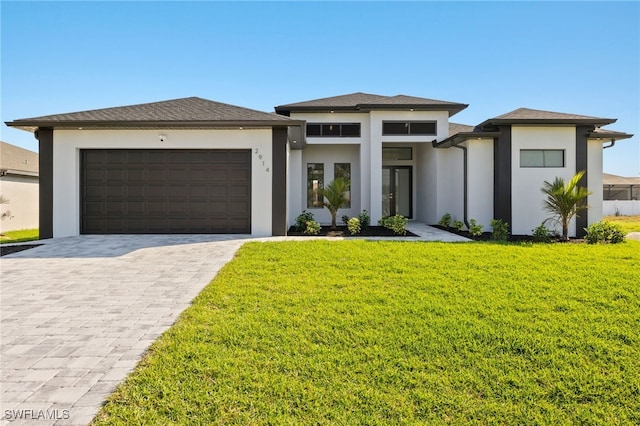 prairie-style house featuring an attached garage, a front lawn, decorative driveway, and stucco siding