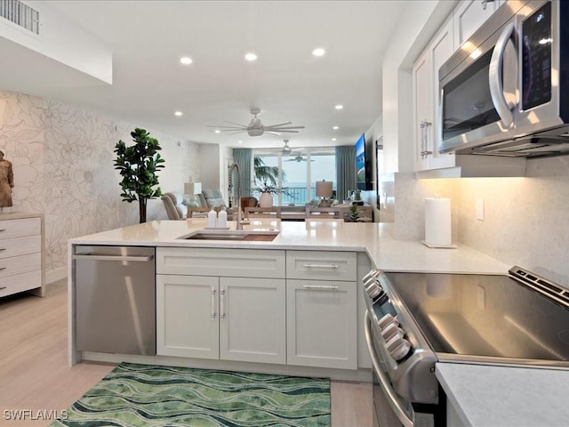 kitchen featuring sink, kitchen peninsula, white cabinets, and appliances with stainless steel finishes