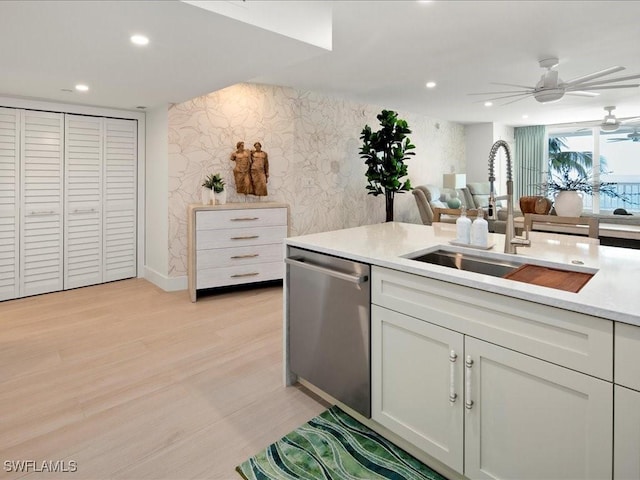 kitchen with sink, white cabinetry, light hardwood / wood-style flooring, dishwasher, and ceiling fan