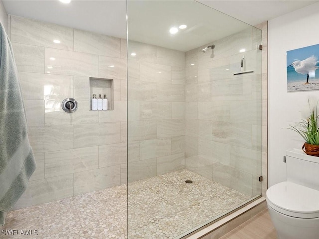 bathroom with a shower with door and toilet