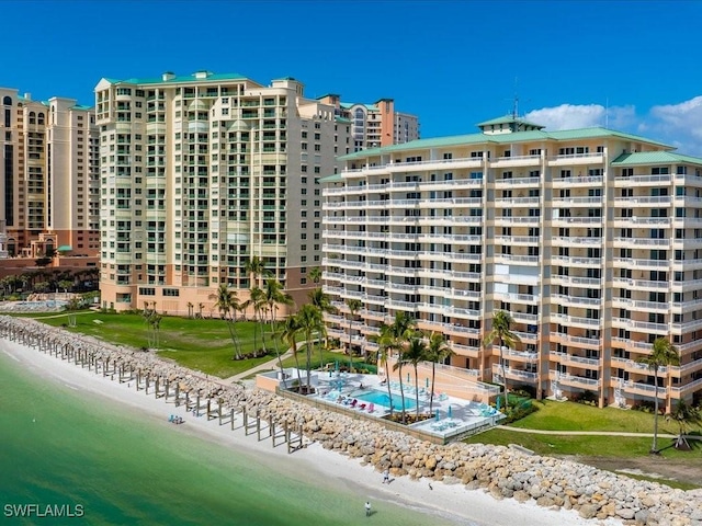 view of building exterior with a water view and a beach view