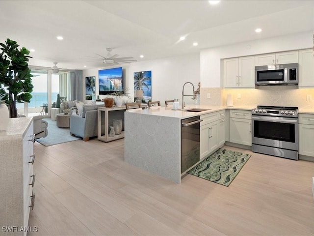 kitchen featuring appliances with stainless steel finishes, white cabinetry, sink, decorative backsplash, and kitchen peninsula