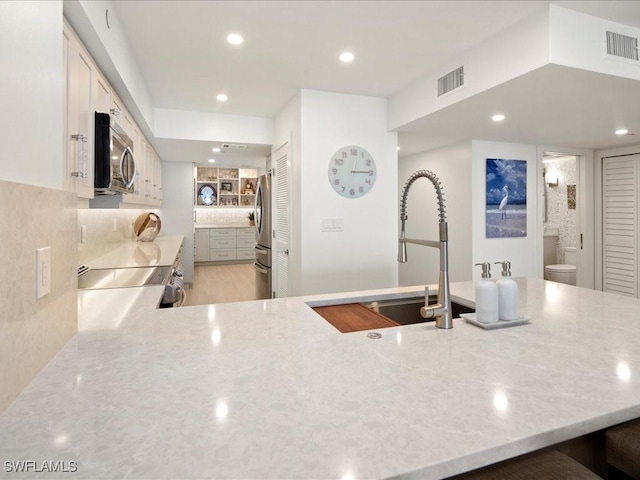 kitchen with stainless steel appliances, sink, decorative backsplash, and white cabinets